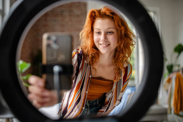 Person adjusts camera setup in front of ring light.