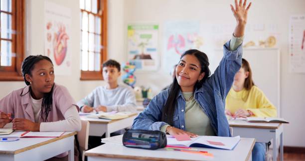 istock Happy girl, students and hands raised with question in classroom for interaction, learning or education at school. Young, group or learners with answer or faq in engagement, quiz or youth development 2174424587