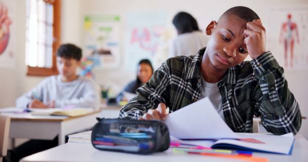 istock Child, student or test with stress for bad result, feedback or exam in classroom at school. Young, kid or teenager with headache, mistake or failure for academic examination, assessment or assignment 2174424600