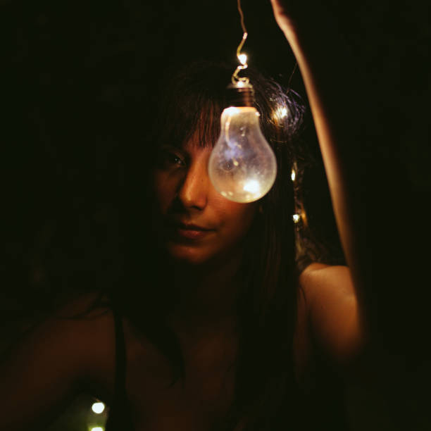 istock Thoughtful woman with burning lightbulb in darkness 2174426925