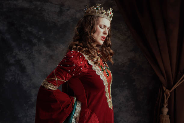istock tired medieval queen in red dress with crown having backache 2174427463