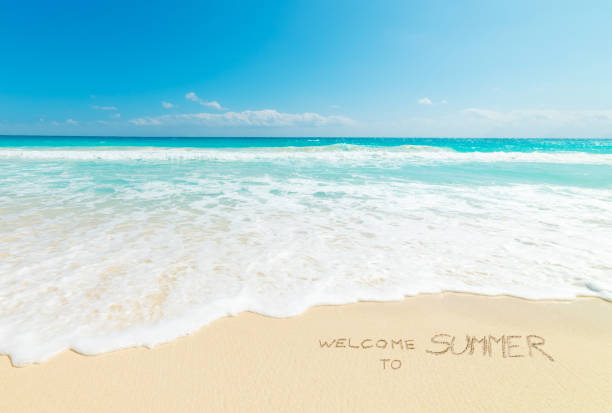 Welcome to Summer written on the sand in a tropical beach