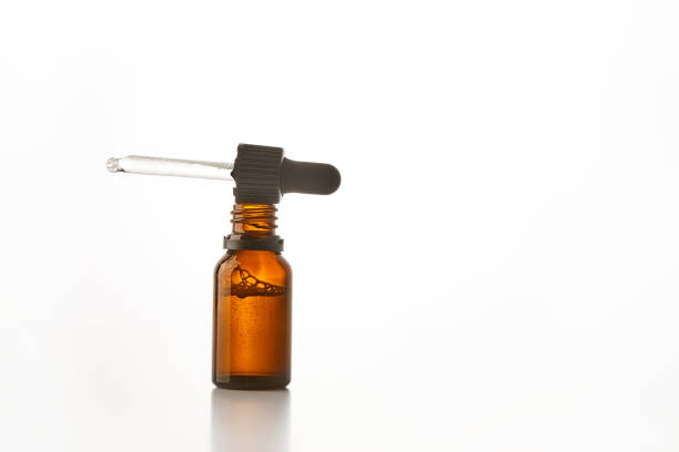 istock Black cap with pipette lies on open brown glass bottle. 2174431052