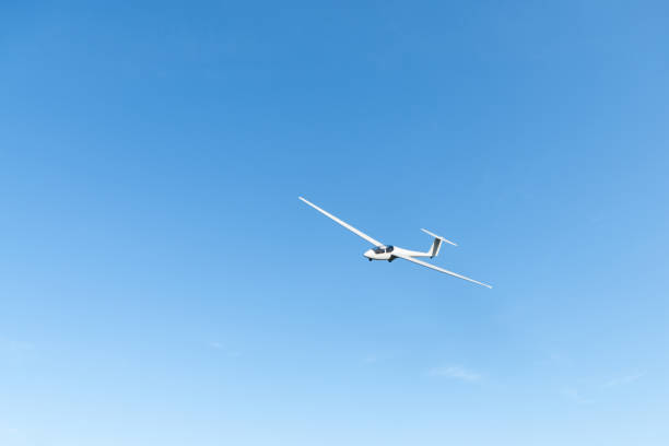A glider gracefully flies across the sky at sunset. The clouds glow in vibrant orange tones, contrasting with the calm evening sky as the aircraft elegantly glides through the dusk.