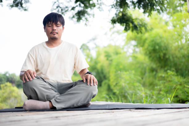 istock A man is sitting on a mat in a park, meditating. 2174438295