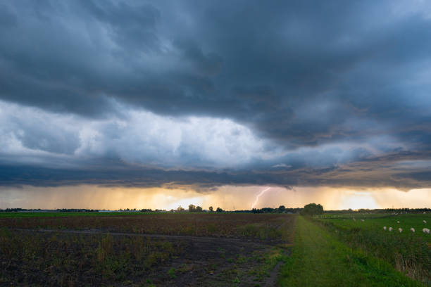 Lightning bolt is hitting the earth from a dark storm cloud during sunset.