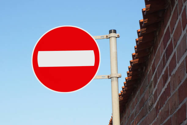 istock No entry road sign mounted on a metal pole. Red brick wall with a blue sky background. Private property. 2174443056