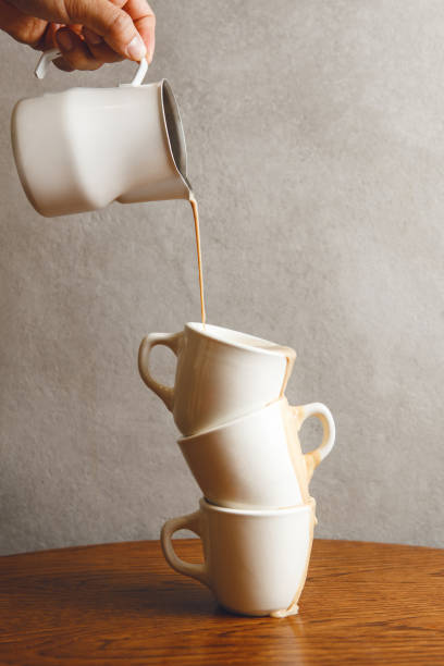 istock Pouring Whipped Milk From Pitcher Into Stacked Espresso Cups for Macchiato Coffee 2174445058