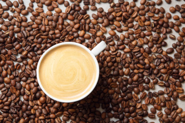 istock Cup of Latte Art Surrounded by Roasted Coffee Beans on Neutral Surface 2174445916