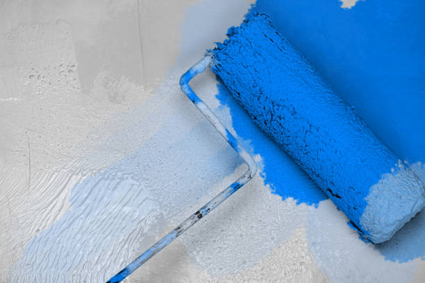 istock Creative graphic concept of paint roller applying fresh blue  color paint onto the white concrete wall. Process of home renovation, improvement and makeover. Copy space. 2174446416