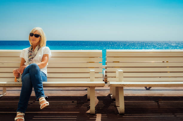 Woman sitting on a bench on the Promenade des Anglais, Nice, France.