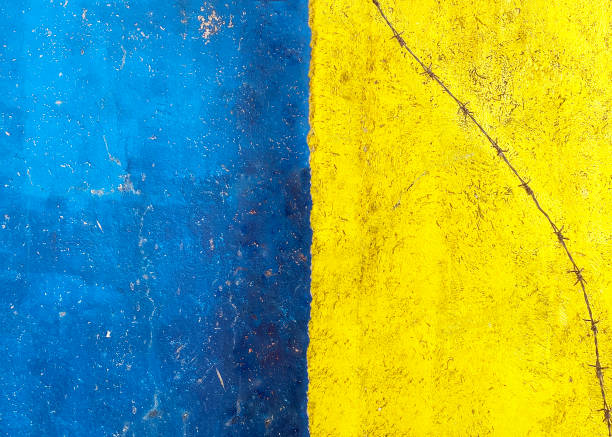 istock yellow-blue concrete wall with barbed wire on it 2174448770