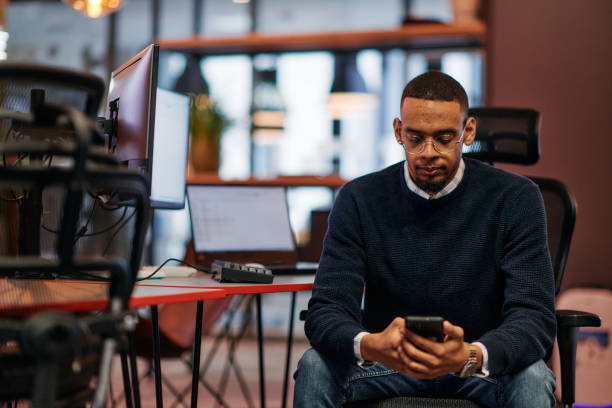 istock After Hours Reflection: African American Man Using Smartphone in Office. 2174456625