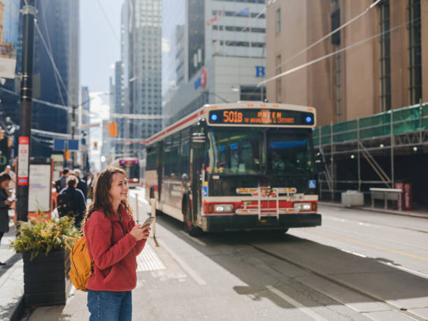 istock Woman using smartphone on the bus stop in Toronto city 2174457703