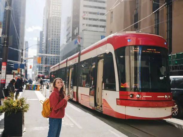Woman using smartphone waiting for the tramway in Toronto Woman using smartphone waiting for the tramway in Toronto