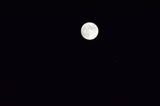 A view of the full moon rising over the horizon in Nelson, British Columbia, Canada.
