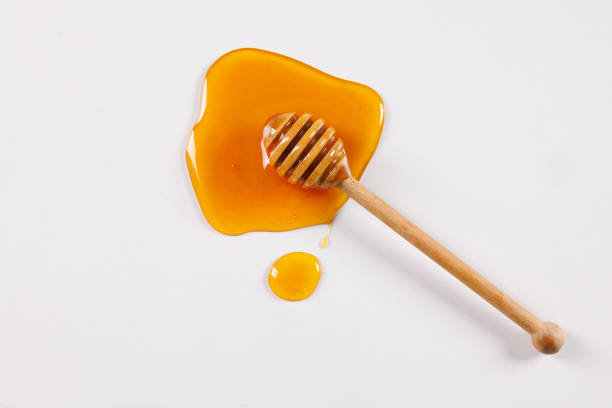 honey spoon with spilled honey on white background, top view, honey benefits concept