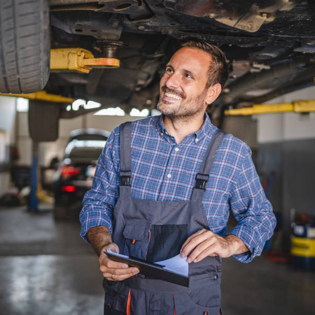 istock Car mechanic check automobile undercarriage system and hold clipboard 2174471470