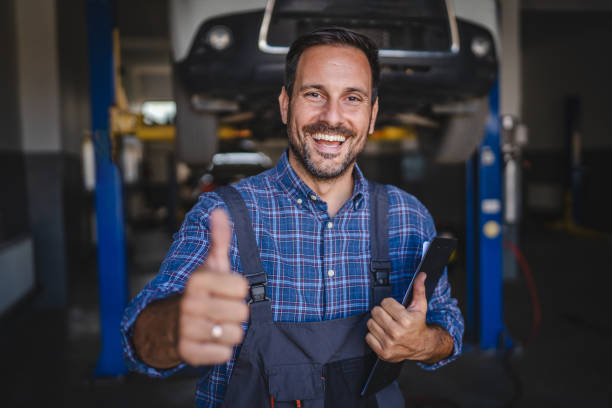 istock Car mechanic making gesture under the car with friendly smile 2174471673