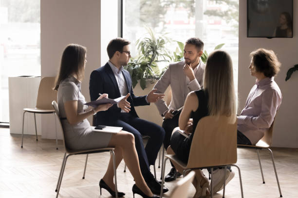 istock Serious boss instructing team of employees sitting in circle 2174478536