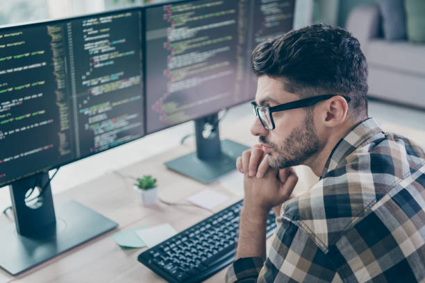 istock Photo of smart minded programmer wear spectacles arms hands chin thinking device program indoors workplace workshop home 2174480100