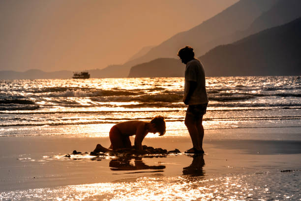 istock Mother and son playing by the sea at sunset. 2174480112
