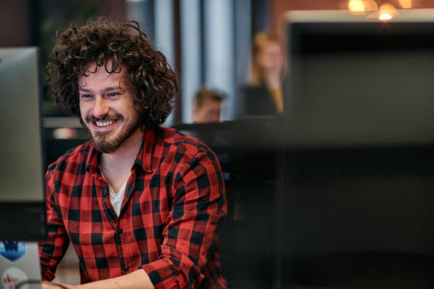 istock Focused Programmer With Afro Hairstyle in Plaid Shirt Working on Computer in Office Environment 2174480683