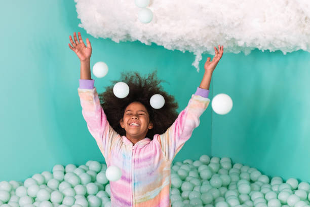Excited black girl playing in ball pit