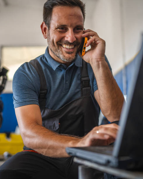 istock Car mechanic work on laptop while talk on mobile phone in garage 2174483491