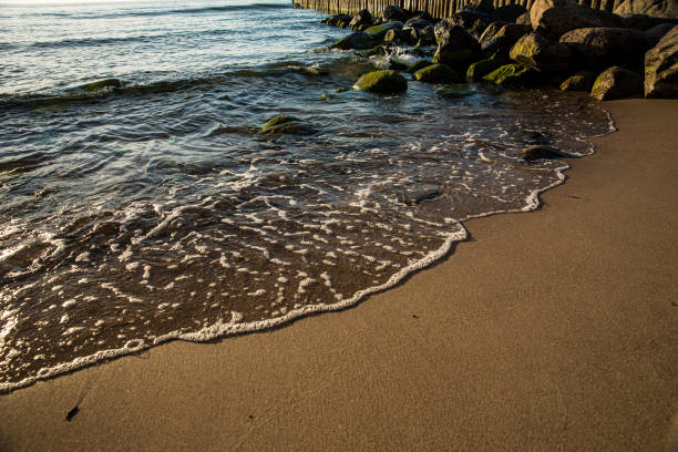 This is a detailed closeup view of a beautiful beach where waves are energetically crashing and gently rolling onto the warm sand