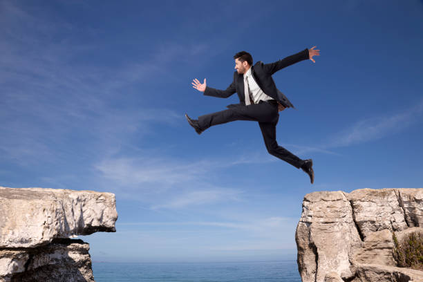 istock A businessman fearlessly leaps between two rocks 2174487610