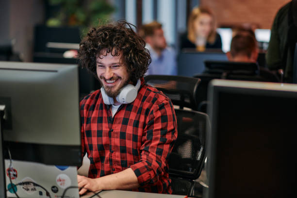 istock Focused Programmer With Afro Hairstyle in Plaid Shirt Working on Computer in Office Environment 2174488009
