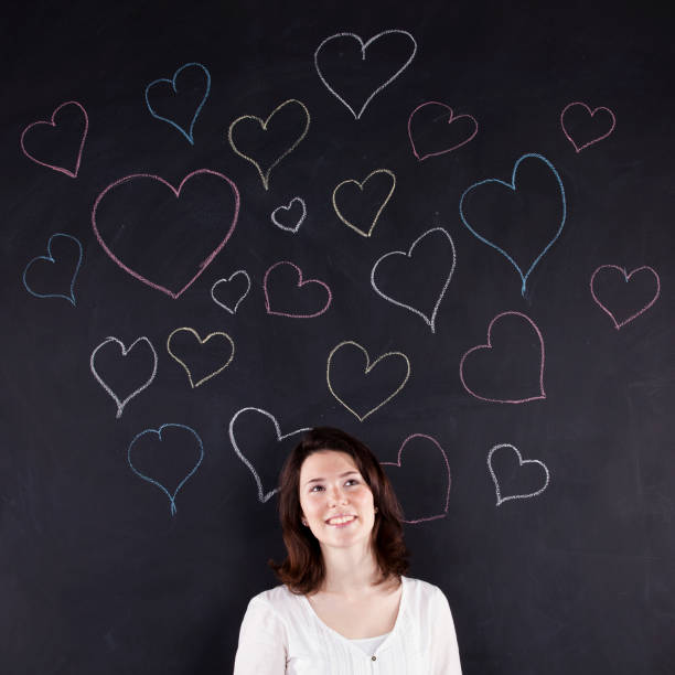 istock Woman stands beside a chalkboard adorned with hand-drawn hearts 2174502103
