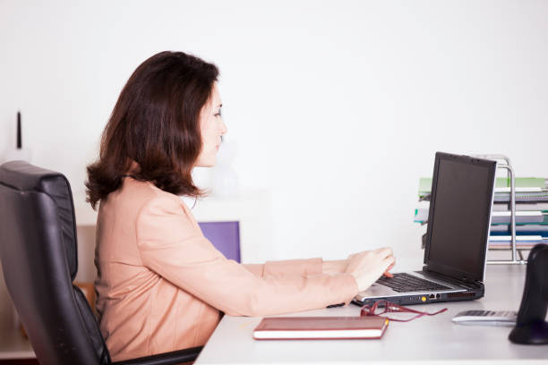 Capturing the essence of a young professional in a dynamic office setting, this image showcases a woman seamlessly managing tasks at her desk. Engaged with her computer, phone, and agenda, she embodies efficiency and ambition.