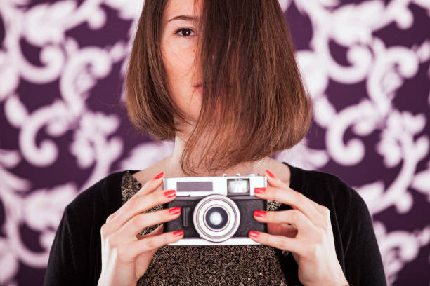 Harmonious blend of past and present, a businesswoman holds a vintage camera, capturing a moment that transcends time. The camera becomes a symbol of creativity and nostalgia. The connection between the modern world of business and the timeless allure of capturing memories.