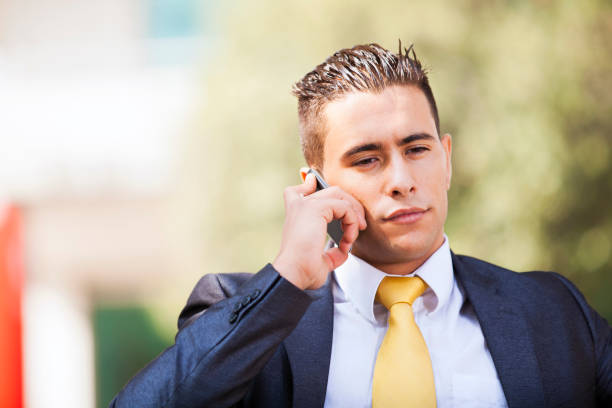 A businessman walking in office buildings area and talking on his smartphone.