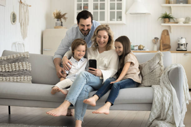 istock Smiling parents with children using cellphone at home 2174504578