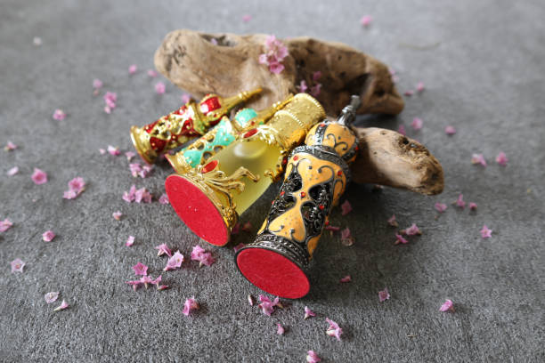 Bottle of perfume with petals on gray stone background.