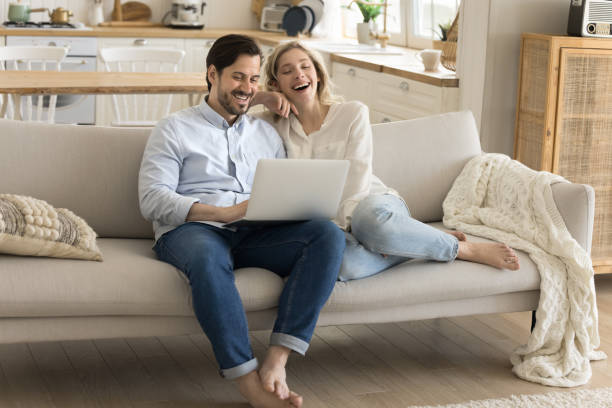 istock Laughing couple relax on couch watching funny blog using laptop 2174506180