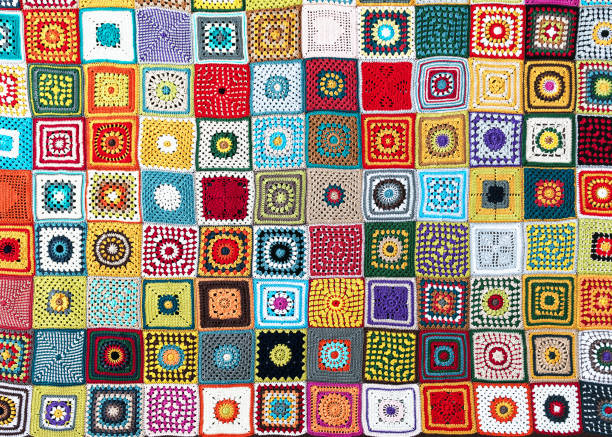 Top view of handmade multi colored plaid make from crochet granny squares with different motifs. Beautiful handicraft product for warm in wintertime.