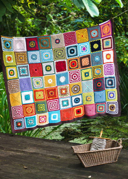 istock Handmade crochet plaid made from cotton granny squares hanging on the string close by a rustic laundry wicker basket. 2174507484