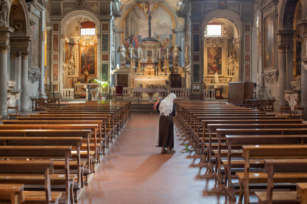 Florence, Italy, June 17, 2023: An elderly nun sweeping the floors inside the Chiesa di Ognissanti, also known as The All Saints Church