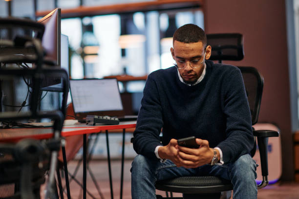 istock After Hours Reflection: African American Man Using Smartphone in Office. 2174514746