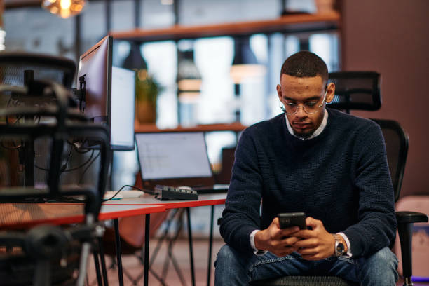 istock After Hours Reflection: African American Man Using Smartphone in Office. 2174516217