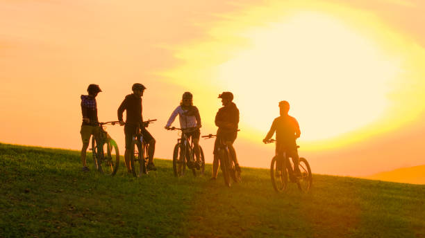 istock SILHOUETTE, LENS FLARE Smiling bikers chatting during break on hilltop at sunset 2174525237