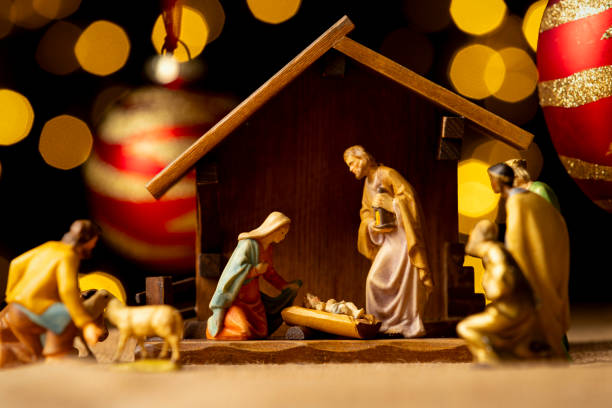A close up of a vintage nativity on the floor under a decorated Christmas tree.