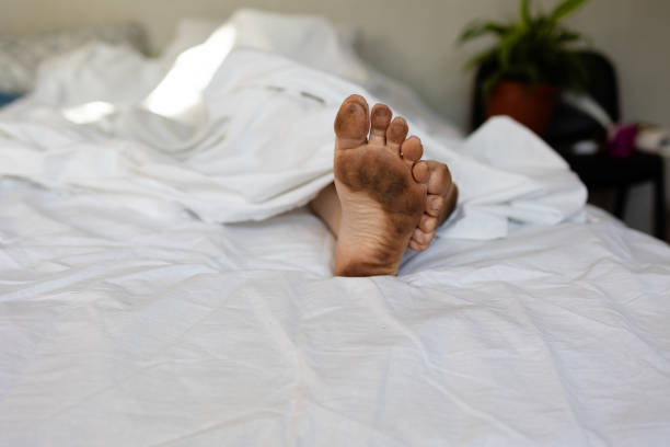 Very dirty feet on snow-white sheets, dirtying a clean bed, a sloppy person who does not observe hygiene High quality photo