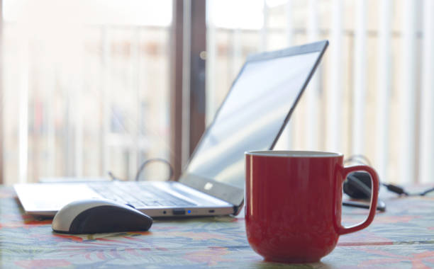 istock A red coffee mug sits on a table next to a laptop computer 2174580326