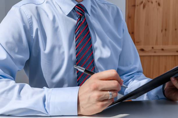 istock A male clerk wearing an elegant shirt and tie writes something down while working 2174581408
