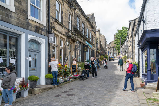 09.08.2024 Haworth, UK. A charming cobblestone street in Haworth, West Yorkshire, lined with historic stone buildings, small shops, and colorful flower displays. Locals and visitors alike enjoy a leisurely stroll through this picturesque village steeped in literary history.